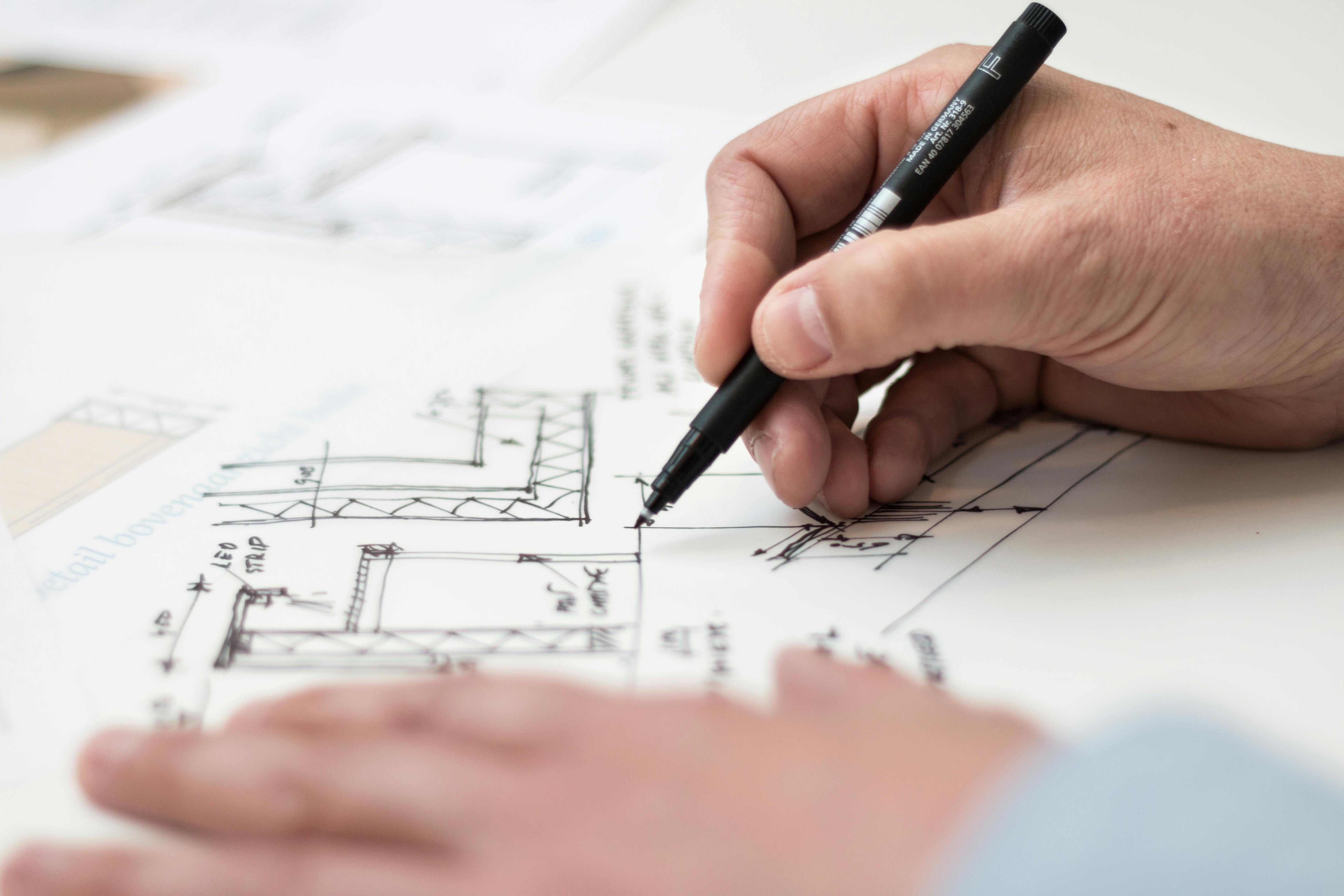 a man holding a pen sketching architecture blueprints